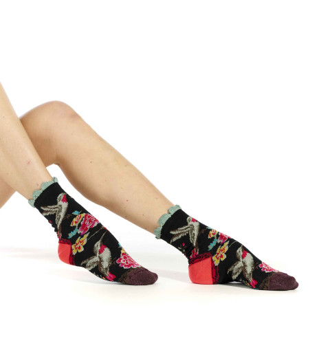 Chaussettes Dub & Drino noires ornées de colibris et de fleurs roses et jaunes. Talon rose et bord-côte festonné vert d’eau.