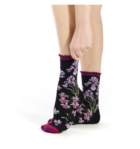 Chaussettes Iridis, Fil de Jour. Noires avec bord-côte festonné violet pailleté et motifs de fleurs roses et violettes.