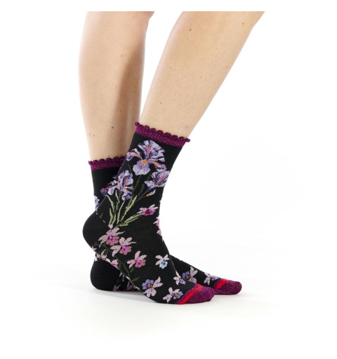 Chaussettes Iridis, Fil de Jour. Noires avec bord-côte festonné violet pailleté et motifs de fleurs roses et violettes.
