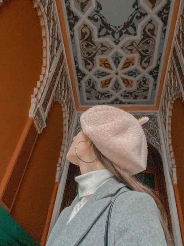 femme en béret qui regarde le plafond